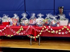 Tables draped with red tablecloths and paper chain garland with raffle baskets