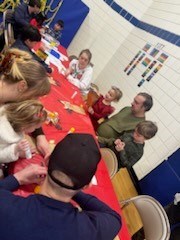 children gathered around table to colour and make paper bag reindeer crafts