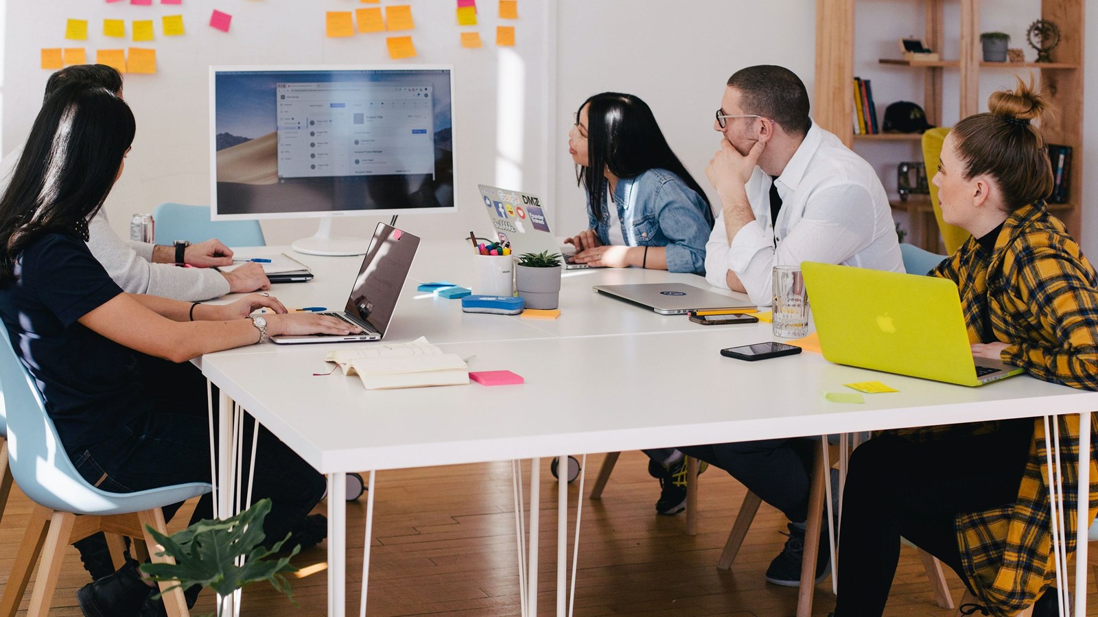 people meeting around a white table with laptops