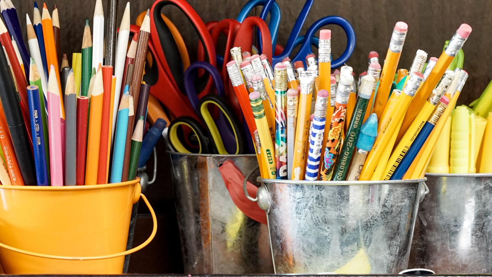 Assorted coloured pencils in metal buckets. 